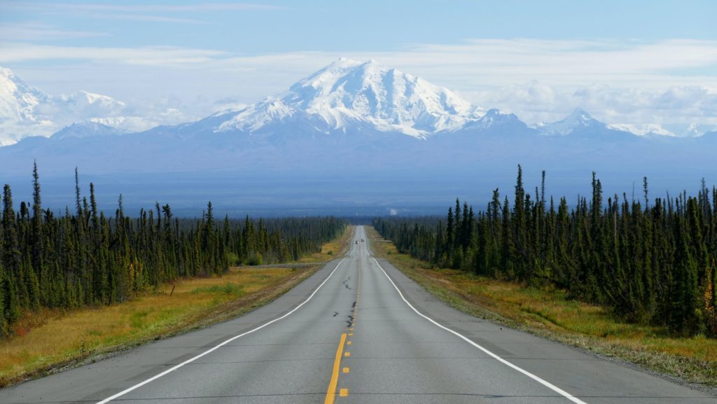 Picture of an empty road leading to snowcapped mountains in Alaska